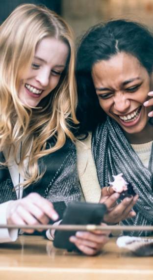 mujeres riendo viendo el telefono
